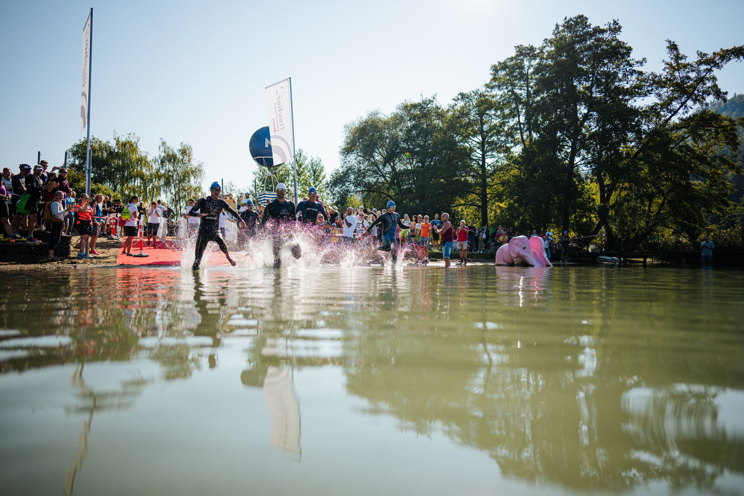 Athletinnen und Athleten laufen beim Start in den Klopeiner See