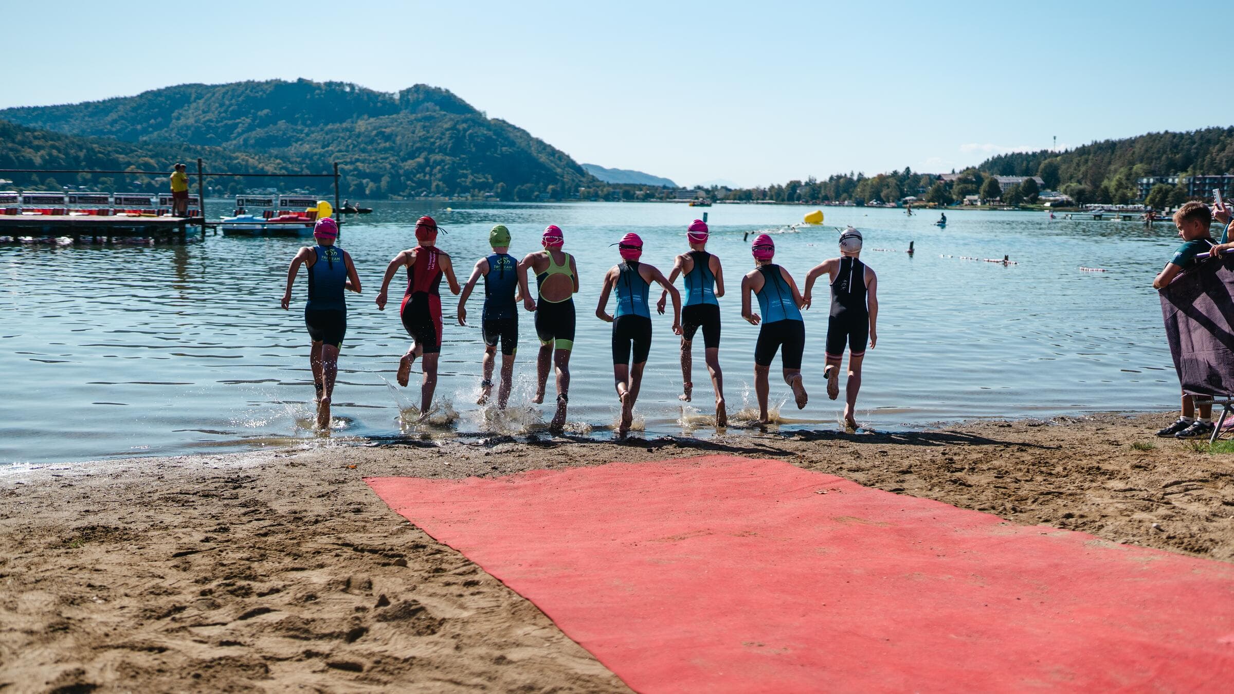Athletinnen und Athleten laufen vom Strand in den Klopeiner See
